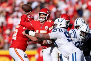 The cover for this NFL odds week 14 article shows Grover Stewart #90 of the Indianapolis Colts being called for roughing the passer on Patrick Mahomes #15 of the Kansas City Chiefs.