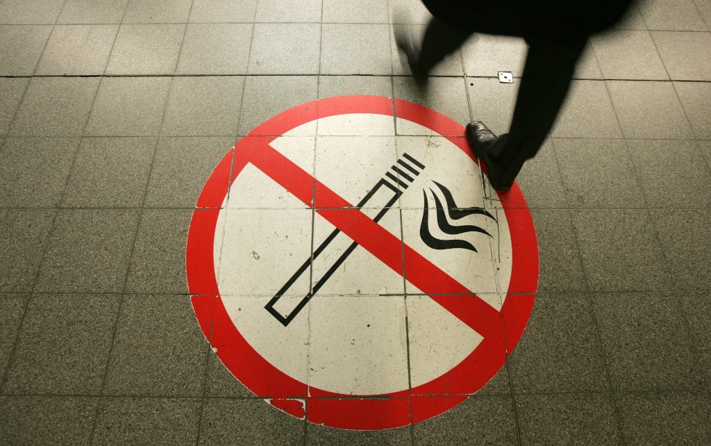 A passenger walks on a no-smoking sign at the Potsdamer Platz train station in Berlin