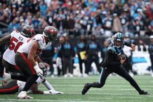 The cover for this NFL Picks Week 17 article shows Bryce Young #9 of the Carolina Panthers scrambling during the game against the Tampa Bay Buccaneers.