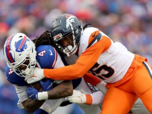 James Cook #4 of the Buffalo Bills carries the ball as Nik Bonitto #15 of the Denver Broncos defends