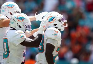 De'Von Achane #28 of the Miami Dolphins is congratulated by his teammates after scoring a touchdown reception against the New England Patriots