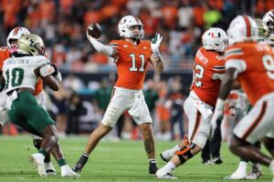 Carson Beck #11 of the Miami Hurricanes rushes against defensive lineman Josh Celiscar #63 of the South Florida Bulls