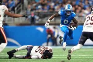Jahmyr Gibbs #0 of the Detroit Lions runs the ball against Dayo Odeyingbo #55 of the Chicago Bears