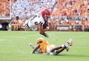 Gunner Stockton #14 of the Georgia Bulldogs runs with the ball while defended by Jalen McMurray #6 of the Tennessee Volunteers