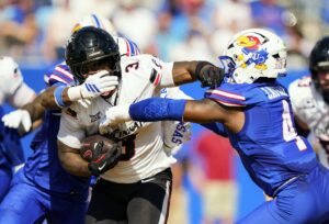 Tawee Walker #3 of the Cincinnati Bearcats runs the ball against Lyrik Rawls #2 and Trey Lathan #4 of the Kansas Jayhawks