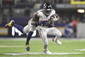 Bijan Robinson #7 of the Atlanta Falcons is tackled by Dallas Turner #15 of the Minnesota Vikings.