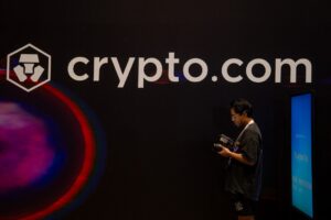 A man stands in front of the Crypto.com logo