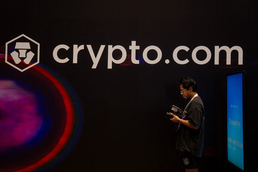 A man stands in front of the Crypto.com logo