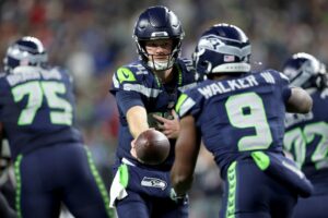 Sam Darnold #14 hands the ball off to Kenneth Walker III #9 against the Houston Texans.