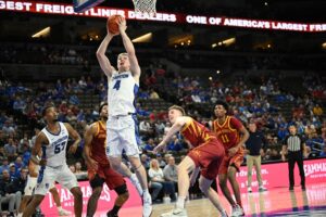 The cover for this college basketball picks today article shows Josh Dix #4 of the Creighton Bluejays scoring against the Iowa State Cyclones