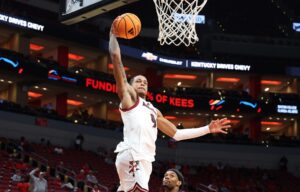 The cover for this college basketball picks today article shows Khani Rooths #9 of the Louisville Cardinals shooting the ball against the South Carolina State Bulldogs