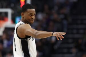 The cover for this NBA player props today article shows De'Aaron Fox #4 of the San Antonio Spurs pointing back towards the Sacramento Kings' bench