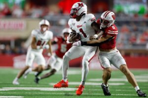 The cover for this Wednesday night college football article shows Christian Alliegro #0 of the Wisconsin Badgers sacks Dequan Finn #1 of the Miami (OH) Redhawks