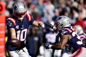 Drake Maye of the New England Patriots hands off the ball to teammate TreVeyon Henderson against the Cleveland Browns. Henderson and the Patriots are featured in our Thursday night football picks.