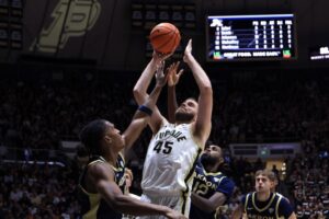 The cover for this college basketball picks today article shows Oscar Cluff #45 of the Purdue Boilermakers shooting against the Akron Zips.