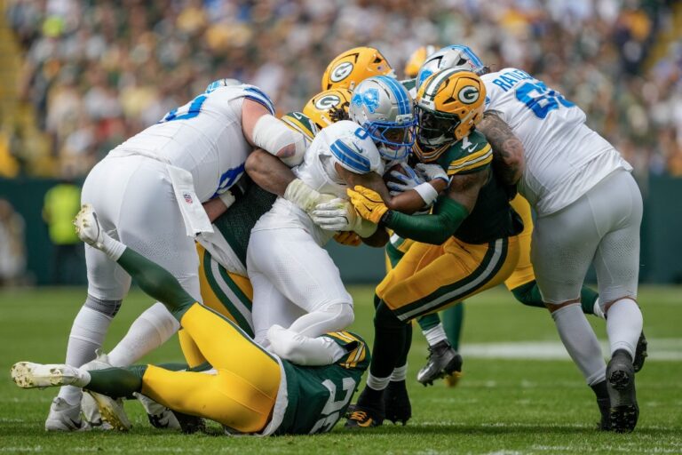 Jahmyr Gibbs #0 of the Detroit Lions runs with the ball as Quay Walker #7 of the Green Bay Packers looks to make a tackle.