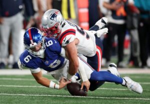 Jaxson Dart #6 of the New York Giants loses the ball as he is tackled by Jack Gibbens #51 of the New England Patriots.