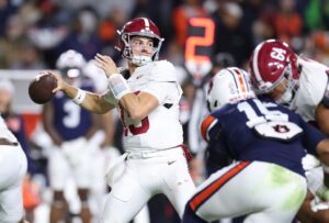 The cover for this Saturday night college football picks article shows Ty Simpson #15 of the Alabama Crimson Tide looks to pass against the Auburn Tigers.