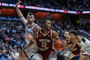 This college basketball picks today article shows Donald Hand Jr. #13 of the Boston College Eagles being defended by Alex Karaban #11 of the Connecticut Huskies.