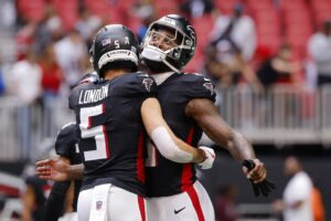 Drake London #5 and Kyle Pitts Sr. #8 of the Atlanta Falcons embrace prior to the game against the Carolina Panthers.