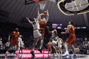 The cover for this college basketball picks today article shows Dominykas Pleta #21 of the Iowa State Cyclones shooting over Oscar Cluff #45 of the Purdue Boilermakers.