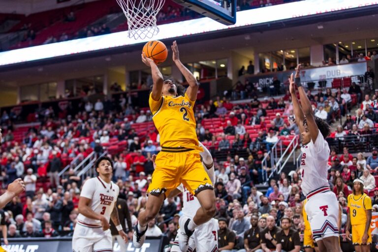 The cover for this college basketball picks today article shows Nasir Meyer #2 of the Wyoming Cowboys shooting the ball during against the Texas Tech Red Raiders.