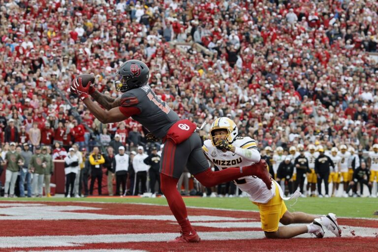 The cover for this College football picks bowls article shows Wide receiver Javonnie Gibson #11 of the Oklahoma Sooners catching an 11-yard touchdown pass against cornerback Drey Norwood #12 of the Missouri Tigers.