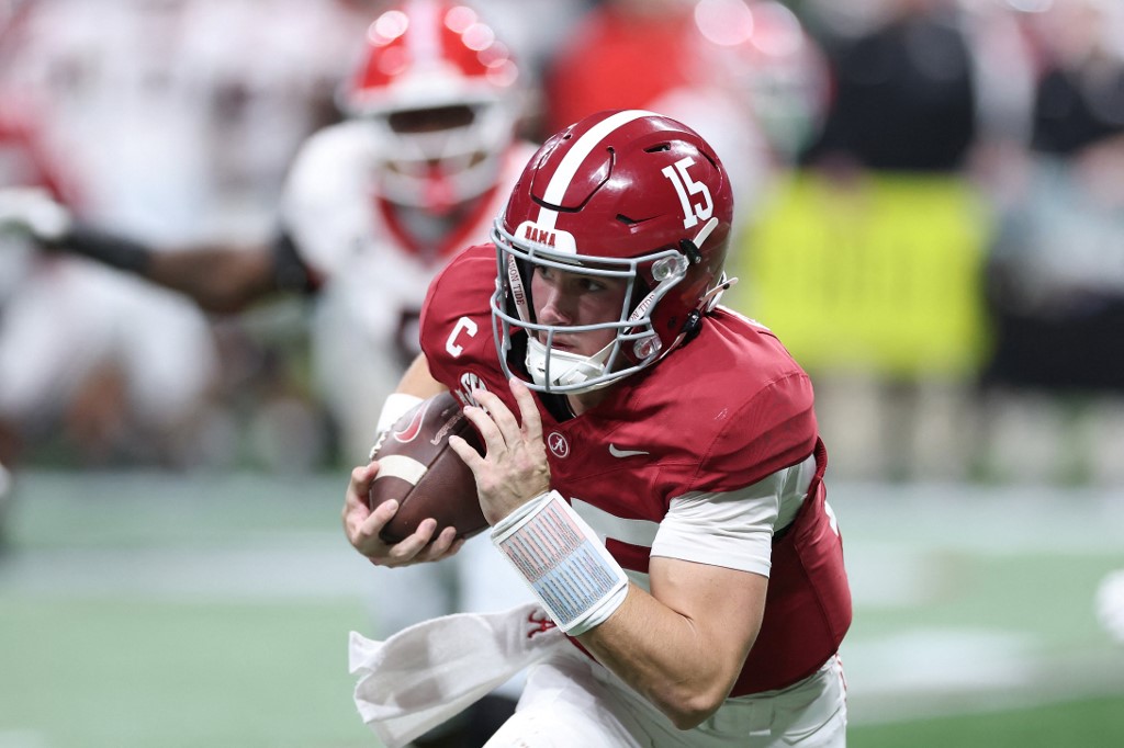 The cover for this Friday night college football picks article show Ty Simpson #15 of the Alabama Crimson Tide running the ball against the Georgia Bulldogs.