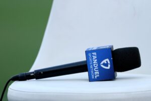 The cover for this article shows a detailed view of a FanDuel Sports Network broadcast microphone.