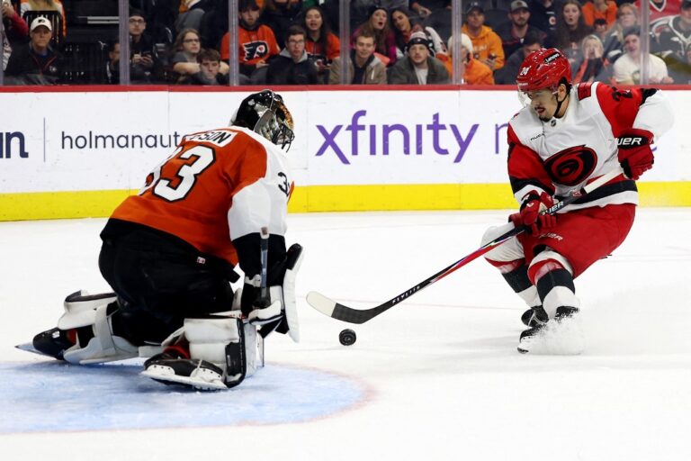 The cover for this NHL picks today article shows Seth Jarvis #24 of the Carolina Hurricanes scoring a goal against Samuel Ersson #33 of the Philadelphia Flyers.