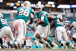Quinn Ewers #14 of the Miami Dolphins hands off to De'Von Achane #28 of the Miami Dolphins