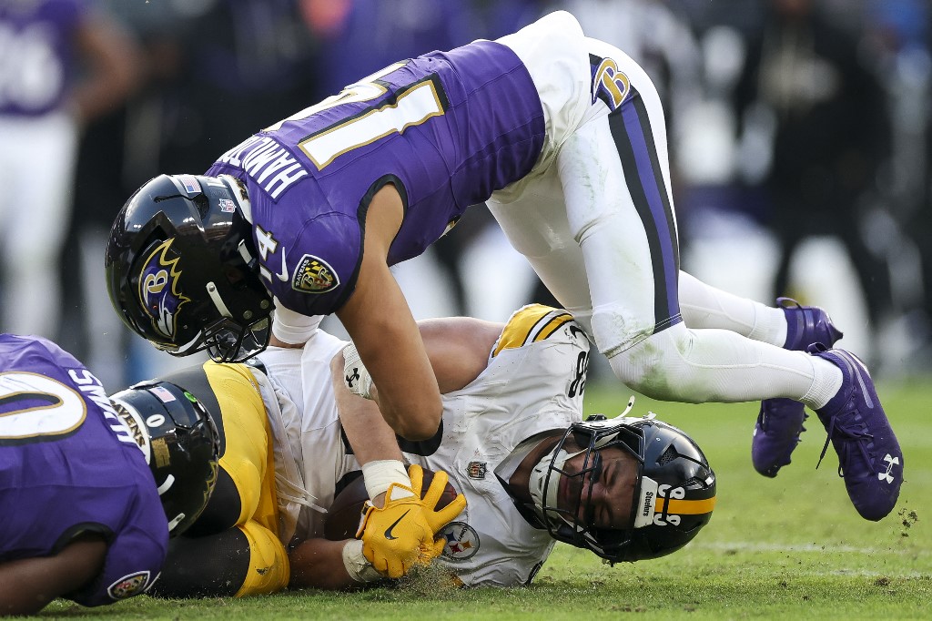 Kyle Hamilton #14 of the Baltimore Ravens tackles Pat Freiermuth #88 of the Pittsburgh Steelers.