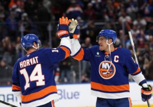 The cover for this NHL parlay picks today article shows Bo Horvat #14 and Anders Lee #27 of the New York Islanders celebrating a victory over the Seattle Kraken.