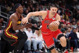 The cover for this NBA player props today article shows Nikola Vucevic #9 of the Chicago Bulls driving against Onyeka Okongwu #17 of the Atlanta Hawks.