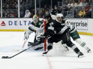 Jeff Malott #39 of the Los Angeles Kings skates around the net in front of Jesper Wallstedt #30 and Brock Faber #7 of the Minnesota Wild