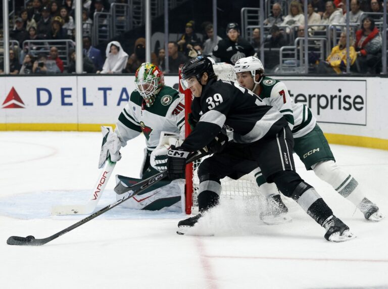 Jeff Malott #39 of the Los Angeles Kings skates around the net in front of Jesper Wallstedt #30 and Brock Faber #7 of the Minnesota Wild