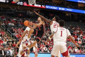 The cover for this college basketball picks today article shows Kingston Flemings #4 of the Houston Cougars shooting the ball as Nick Pringle #23 of the Arkansas Razorbacks defends.