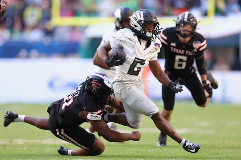 The cover for this college football picks article shows David Bailey #31 of the Texas Tech Red Raiders tackling Noah Whittington #6 of the Oregon Ducks.