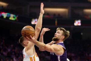 The cover for this NBA player props today article shows Domantas Sabonis #11 of the Sacramento Kings being guarded by Kristaps Porzingis #8 of the Atlanta Hawks.
