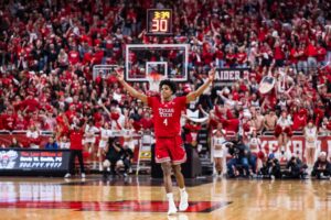 The cover for this college basketball picks today article shows Christian Anderson #4 of the Texas Tech Red Raiders gesturing after making a three-point basket during the second half of the game against the BYU Cougars.