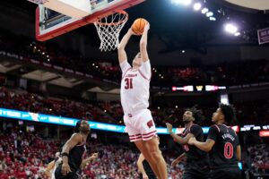 The cover for this college basketball picks today article shows Nolan Winter #31 of the Wisconsin Badgers scoring on a dunk during the second half of the game against the Rutgers Scarlet Knights.