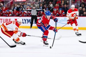Cole Caufield #13 of the Montréal Canadiens shoots the puck as Jonathan Huberdeau #10 of the Calgary Flames.