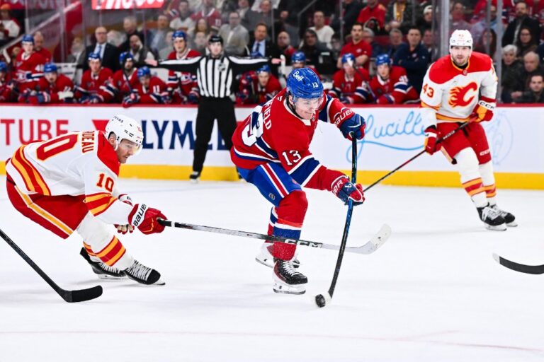Cole Caufield #13 of the Montréal Canadiens shoots the puck as Jonathan Huberdeau #10 of the Calgary Flames.