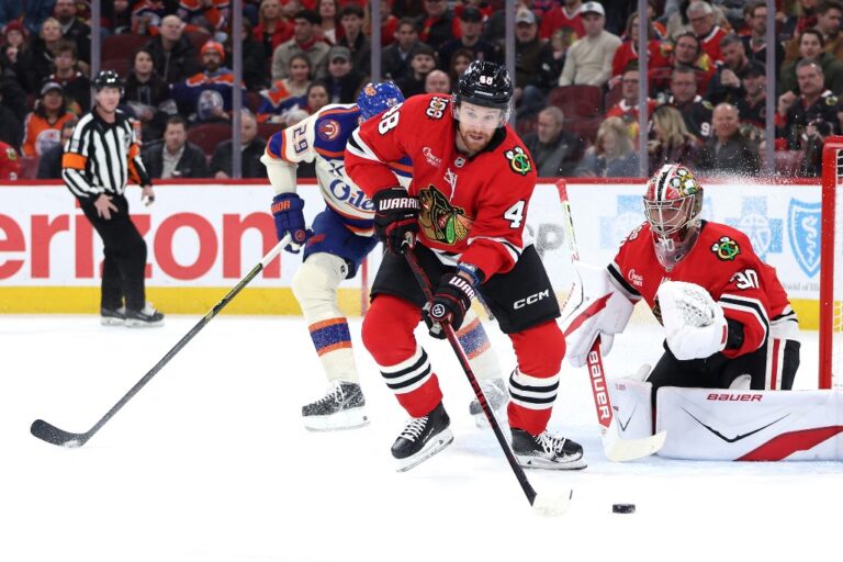 The cover for this NHL picks today article shows Matt Grzelcyk #48 of the Chicago Blackhawks clearing a puck during the first period against the Edmonton Oilers.