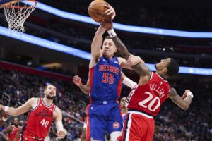 Duncan Robinson #55 of the Detroit Pistons and John Collins #20 of the Los Angeles Clippers reach for a rebound.