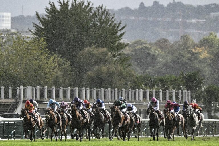 Jockeys race in heavy rainfall during a horse racing event.