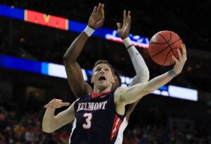 The cover for this college basketball picks today article shows Dylan Windler #3 of the Belmont Bruins taking a shot against Bruno Fernando #23 of the Maryland Terrapins in the second half during the first round of the 2019 NCAA Men's Basketball Tournament.